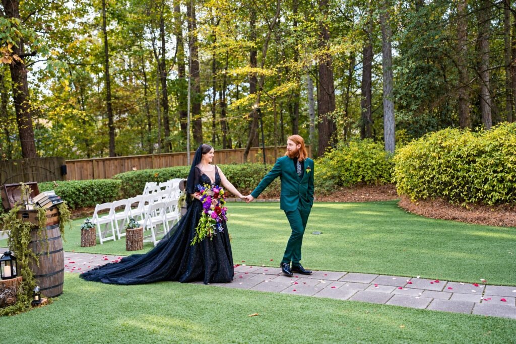 Parker and Olivia holding hands on a garden path beside rows of white ceremony chairs