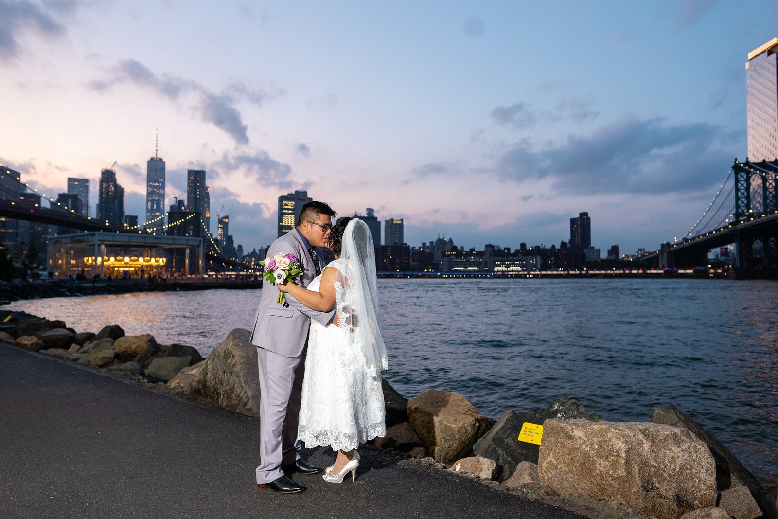 The couple kiss beside the river as the skyline turns to dusk.