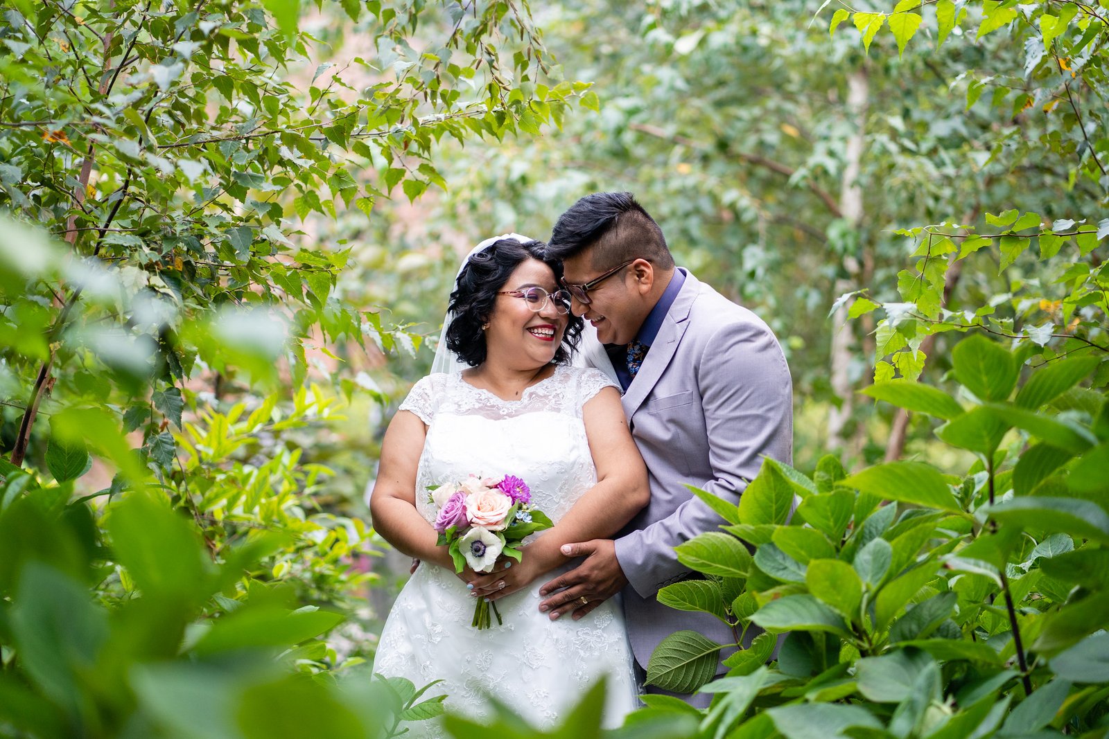 Brenda and David laugh together beneath leafy branches.