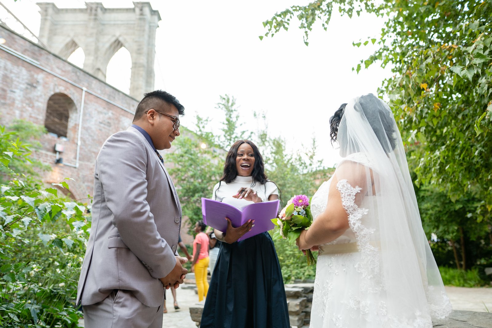 The couple and officiant share a laugh during the garden ceremony.