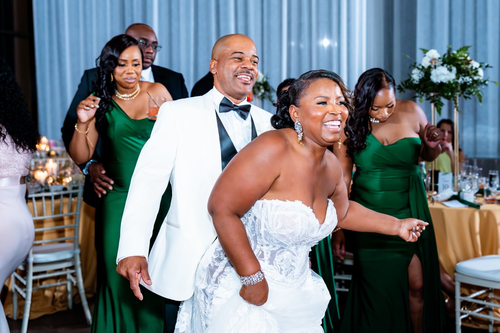 The bride and groom laugh and dance together among their guests.