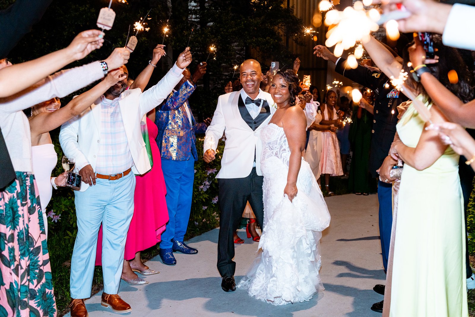 The newlyweds smile beneath sparklers held aloft by their guests.