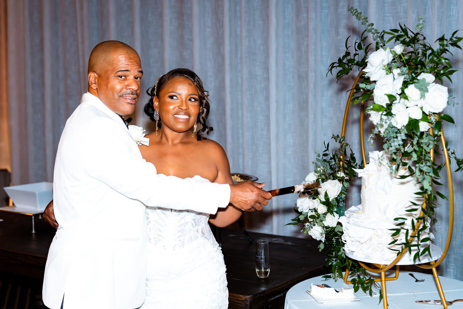 The newlyweds smile while cutting their wedding cake together.