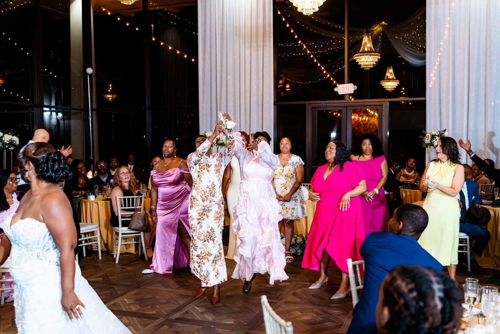 Guests reach up together to catch the bride’s bouquet during the reception.