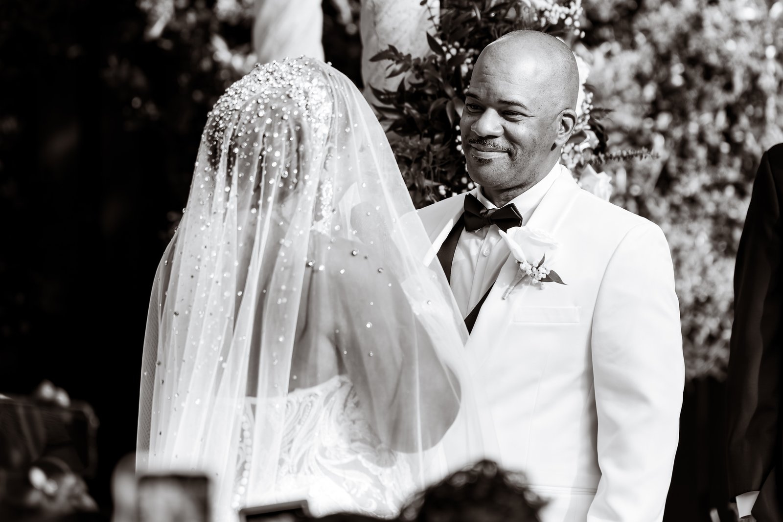The groom smiling at the bride through her veil during the ceremony.