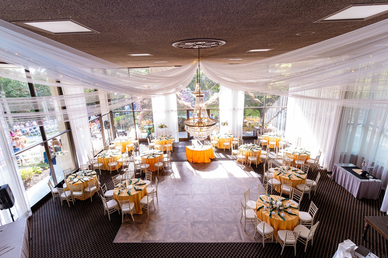 The Atrium reception room set with gold linens, white draping and a chandelier.
