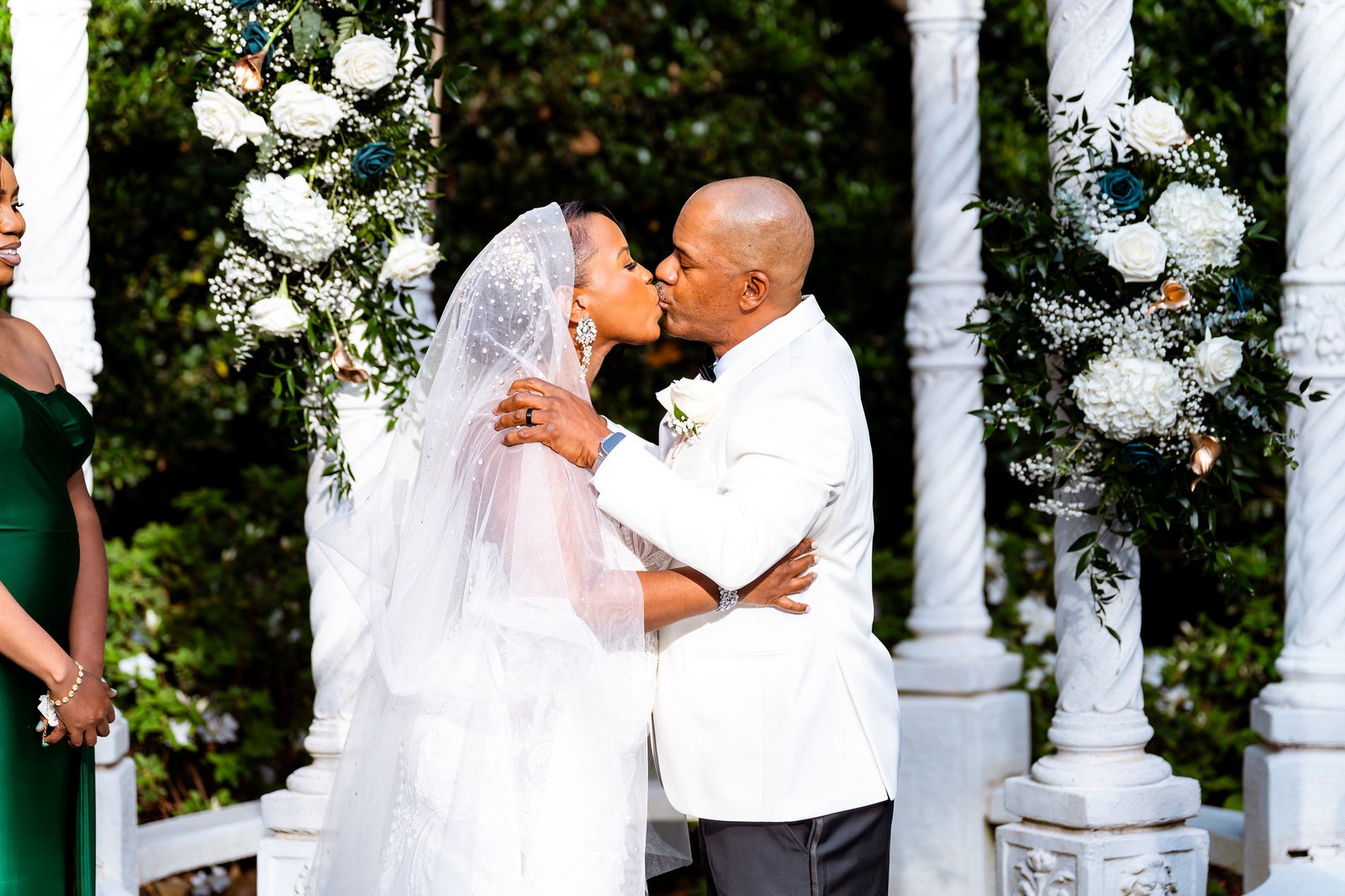 The newlyweds kissing beneath the decorated ceremony gazebo.