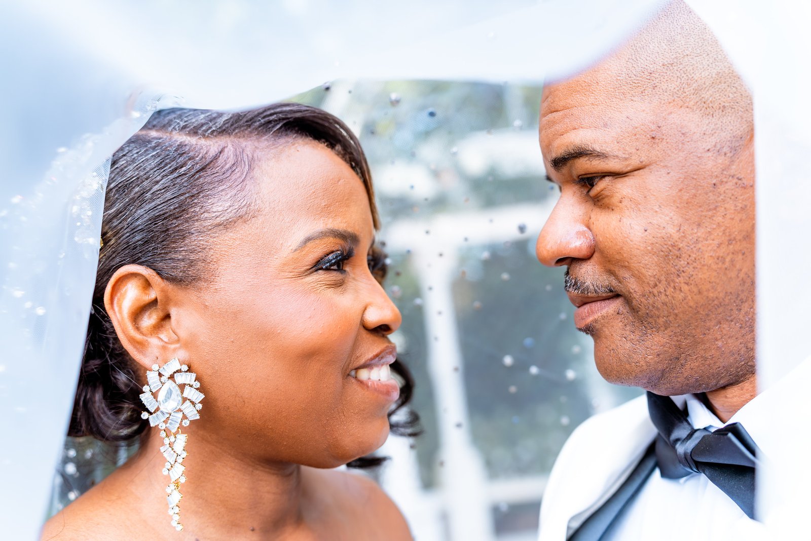 The bride and groom look into each other’s eyes beneath her veil.