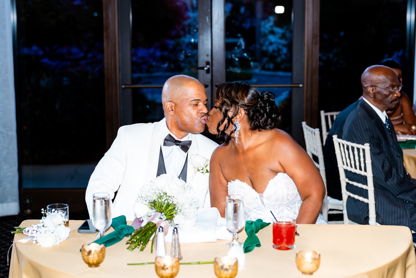 The newlyweds share a kiss at their reception table.