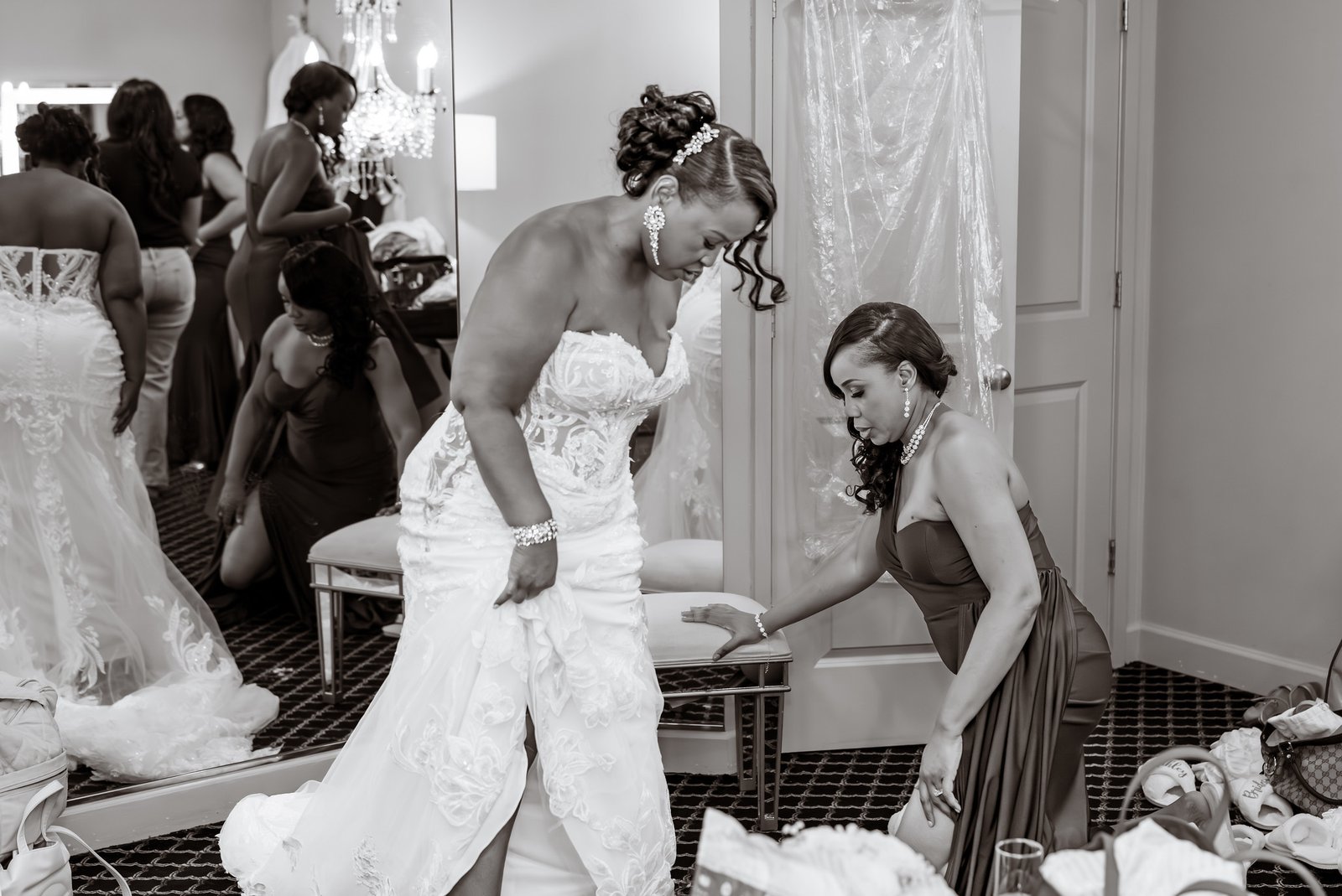 The bride having her wedding dress adjusted in front of a mirror.