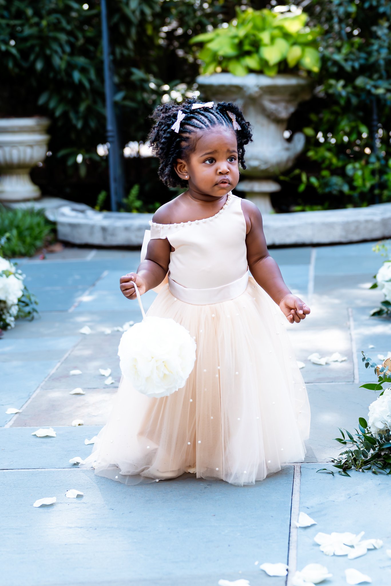 A flower girl carrying a white pomander along the ceremony aisle.