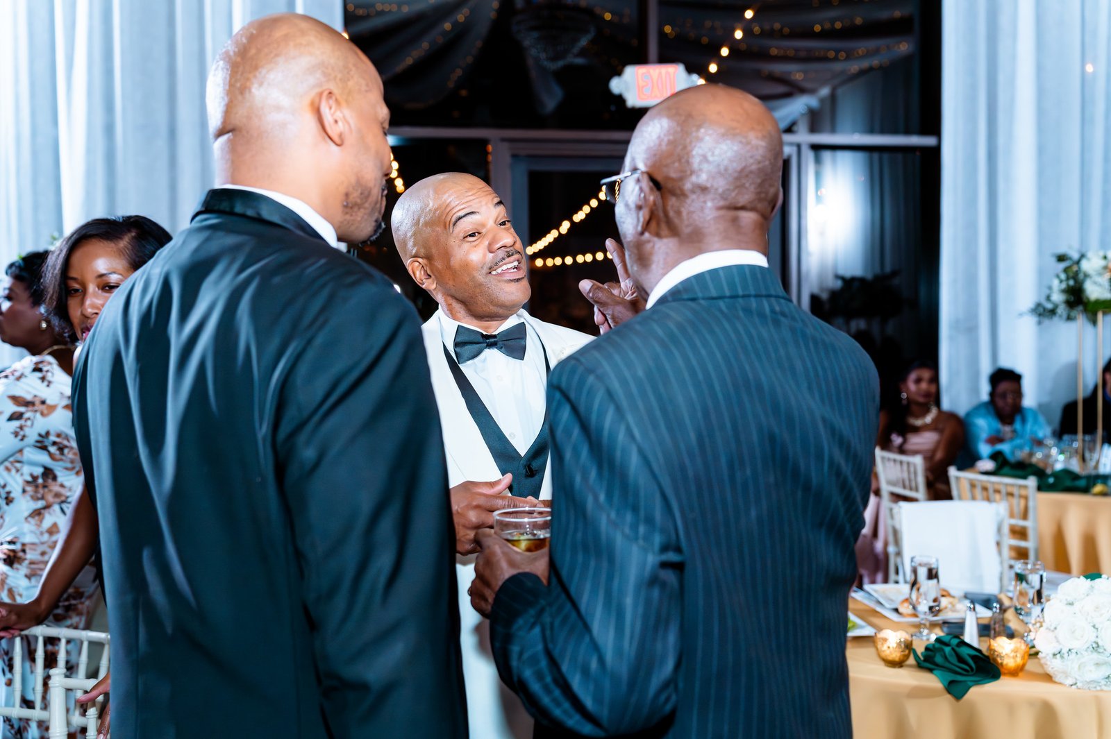 The groom chats animatedly with two guests at the reception.