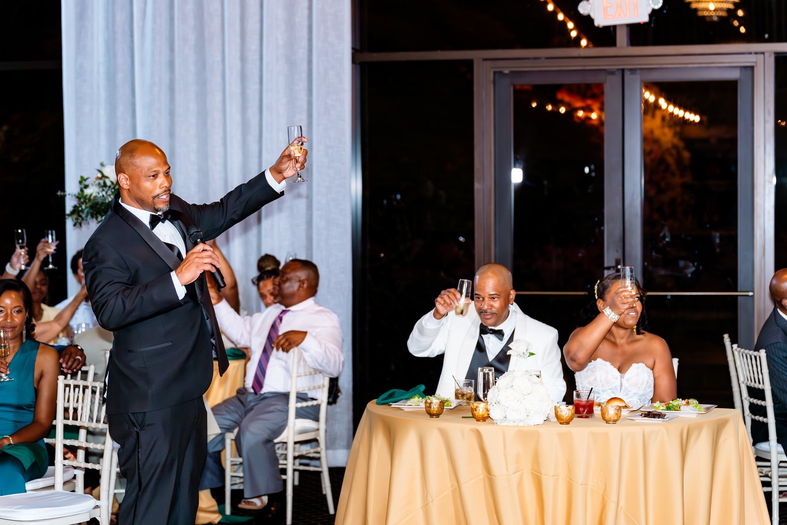 A speaker raises a glass as the newlyweds join a reception toast.