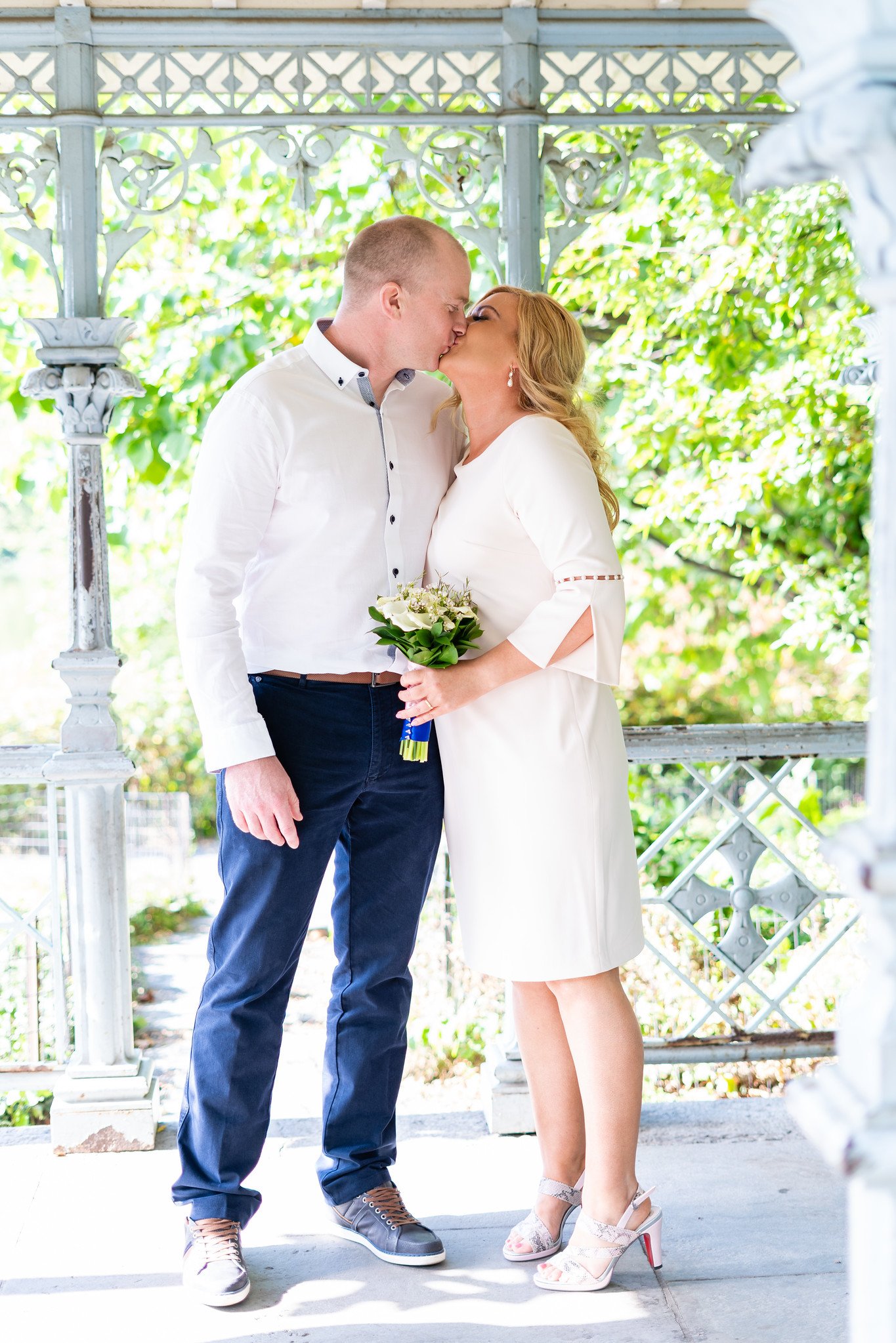 The newlyweds kiss beneath a wooden gazebo.