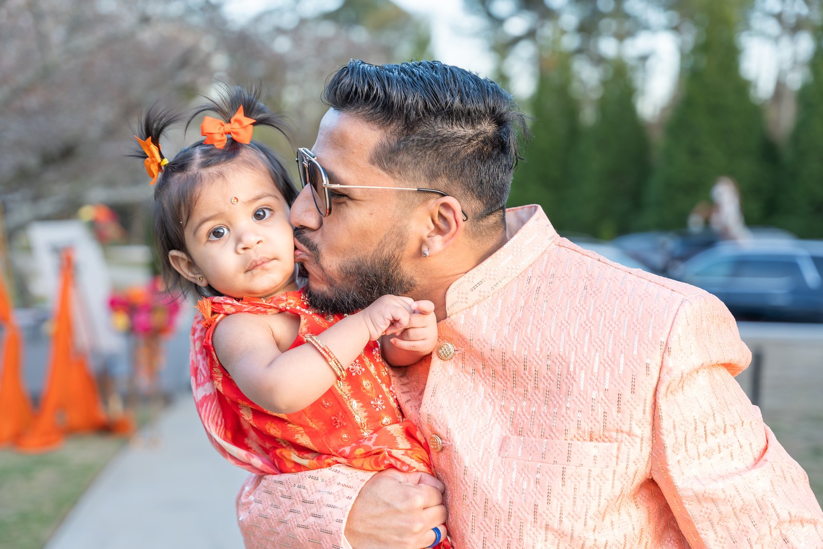 A guest kisses a young child's cheek during the outdoor celebration.