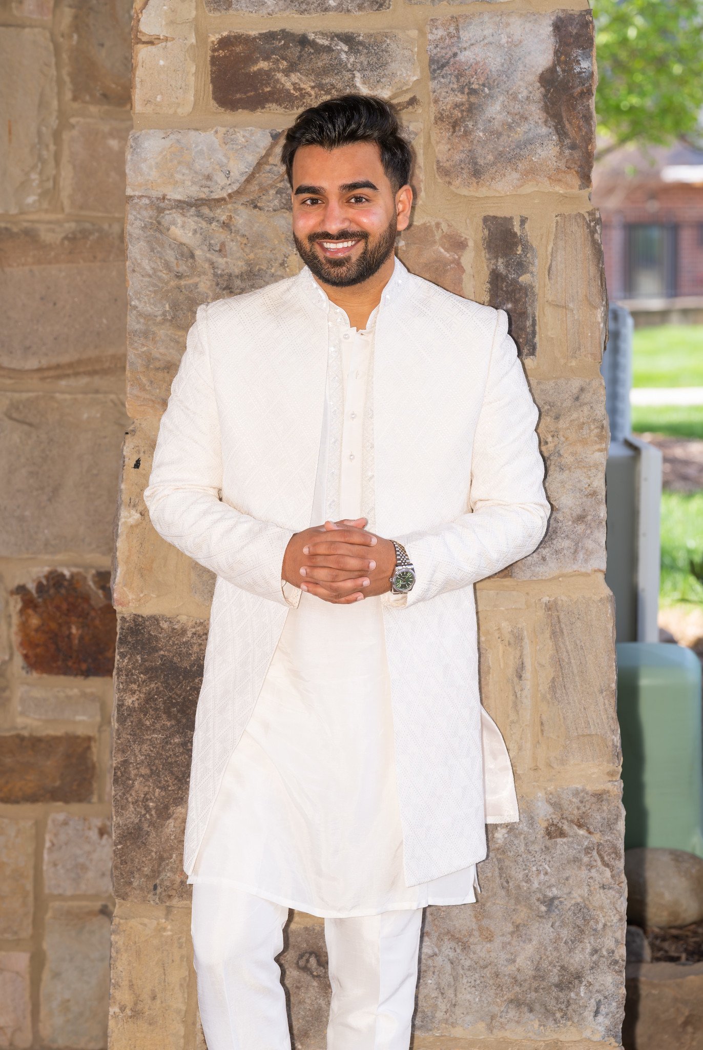 Shahzain in an ivory suit beneath a stone archway