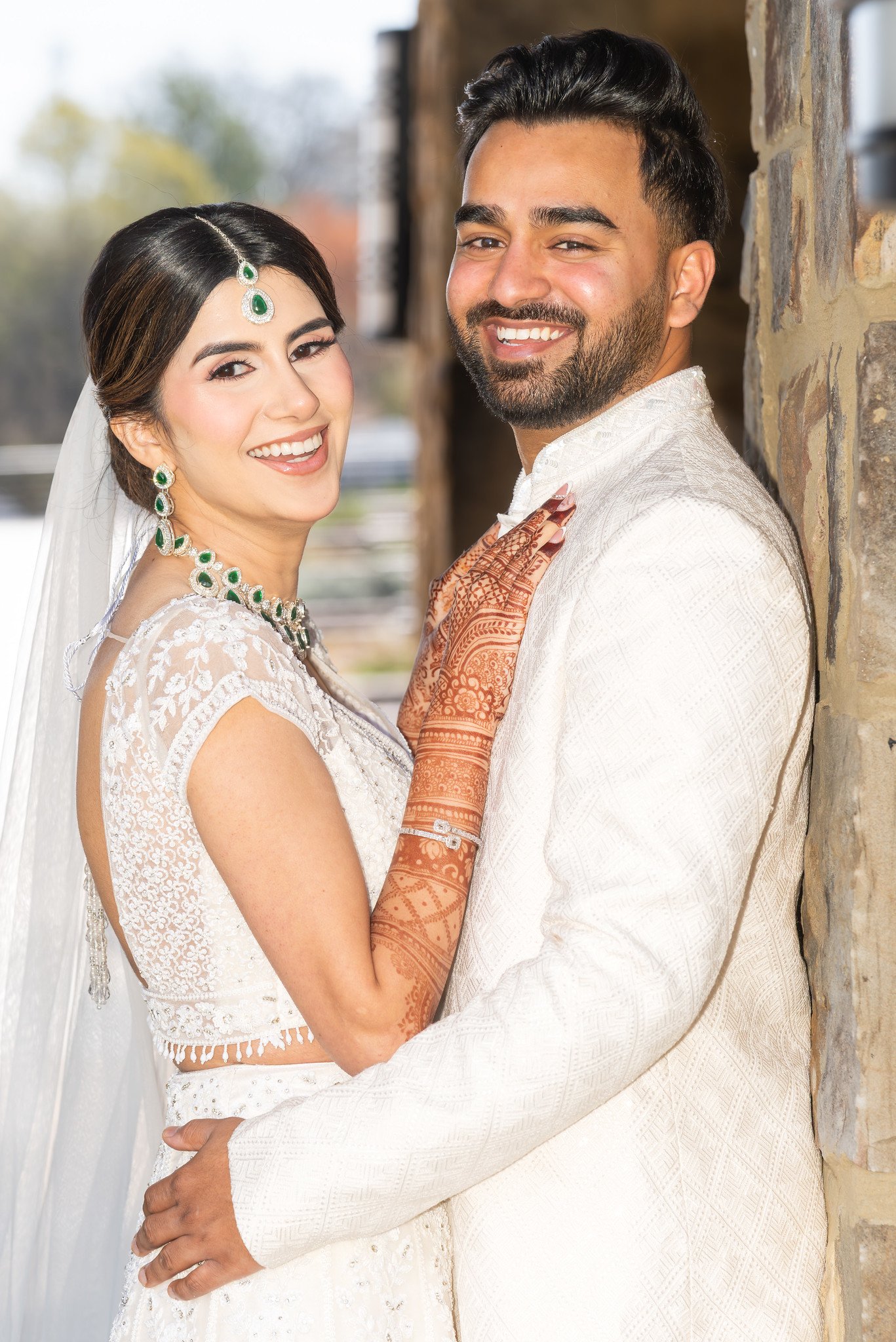 Mehreen and Shahzain smile together beside a stone column