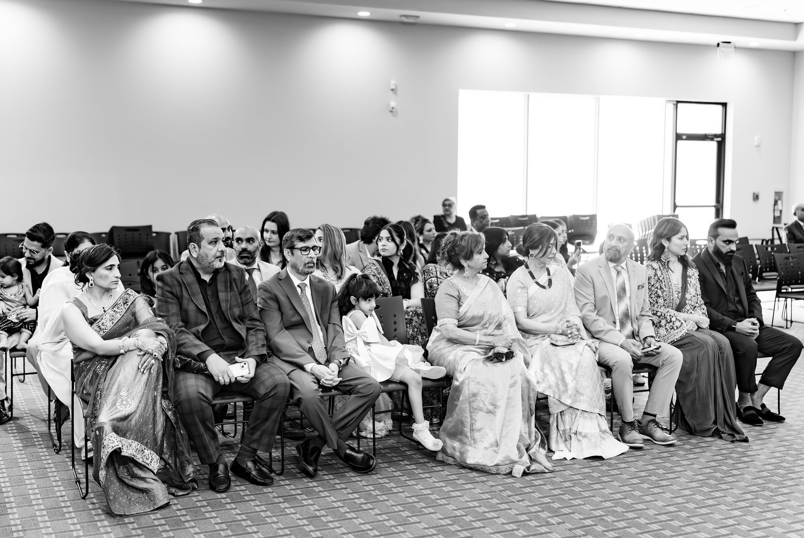 Family and guests watch the ceremony in black and white