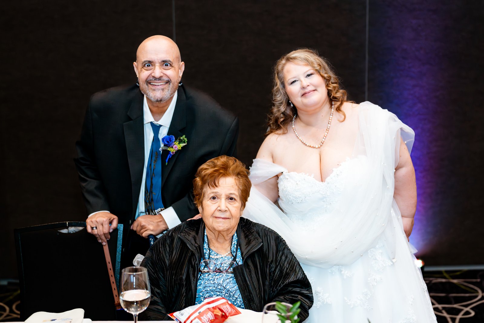 The couple pose beside a seated family member