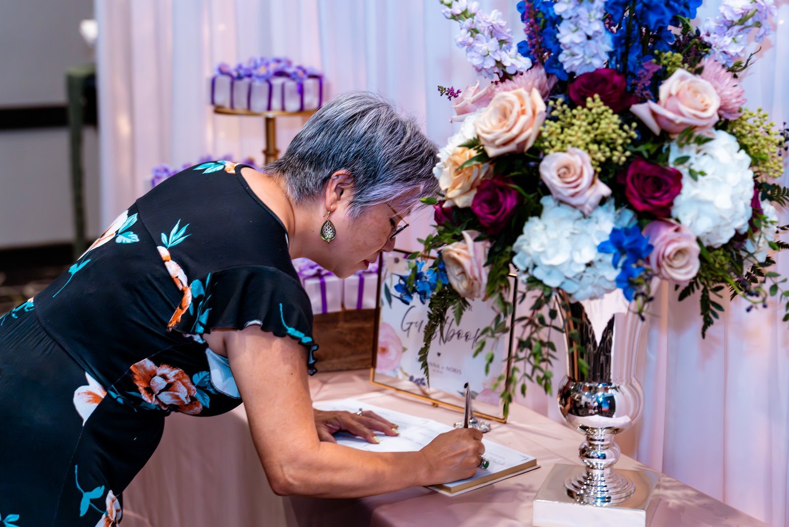 A guest signs the wedding guest book beside flowers