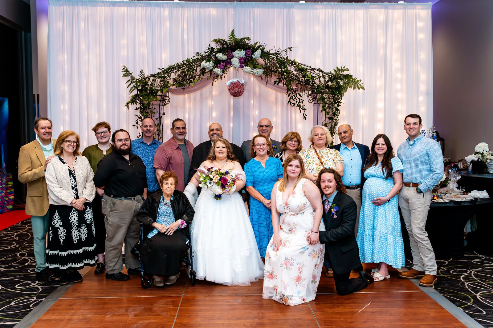 The couple gather with a large family group beneath the arch
