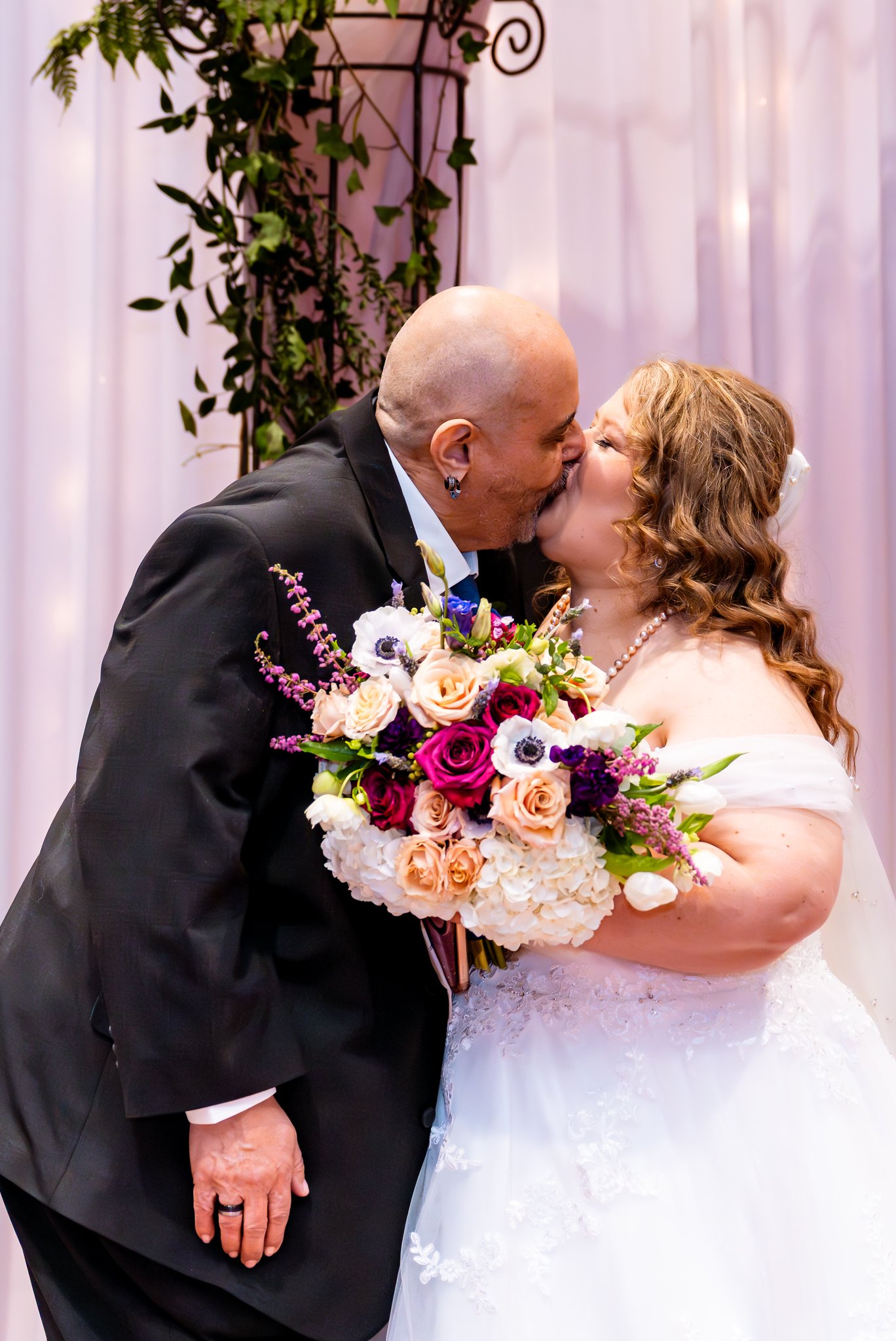 Noris and Towanna kiss beneath the ceremony arch