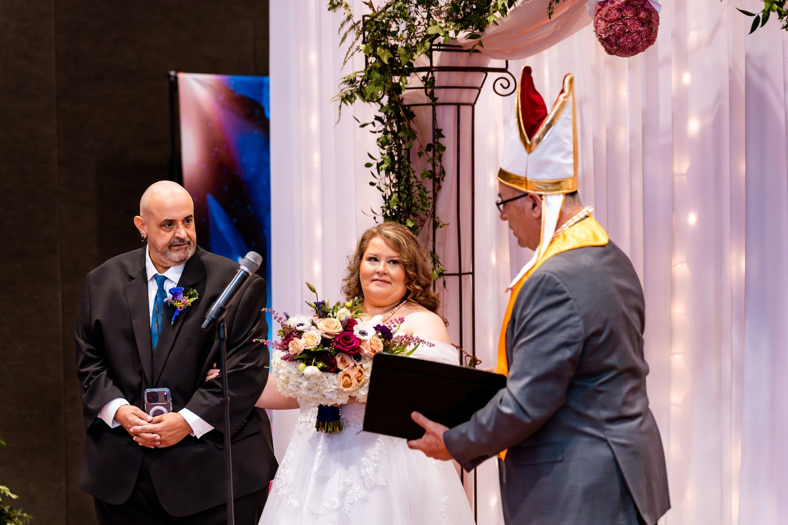 Noris and Towanna stand beneath the floral ceremony arch