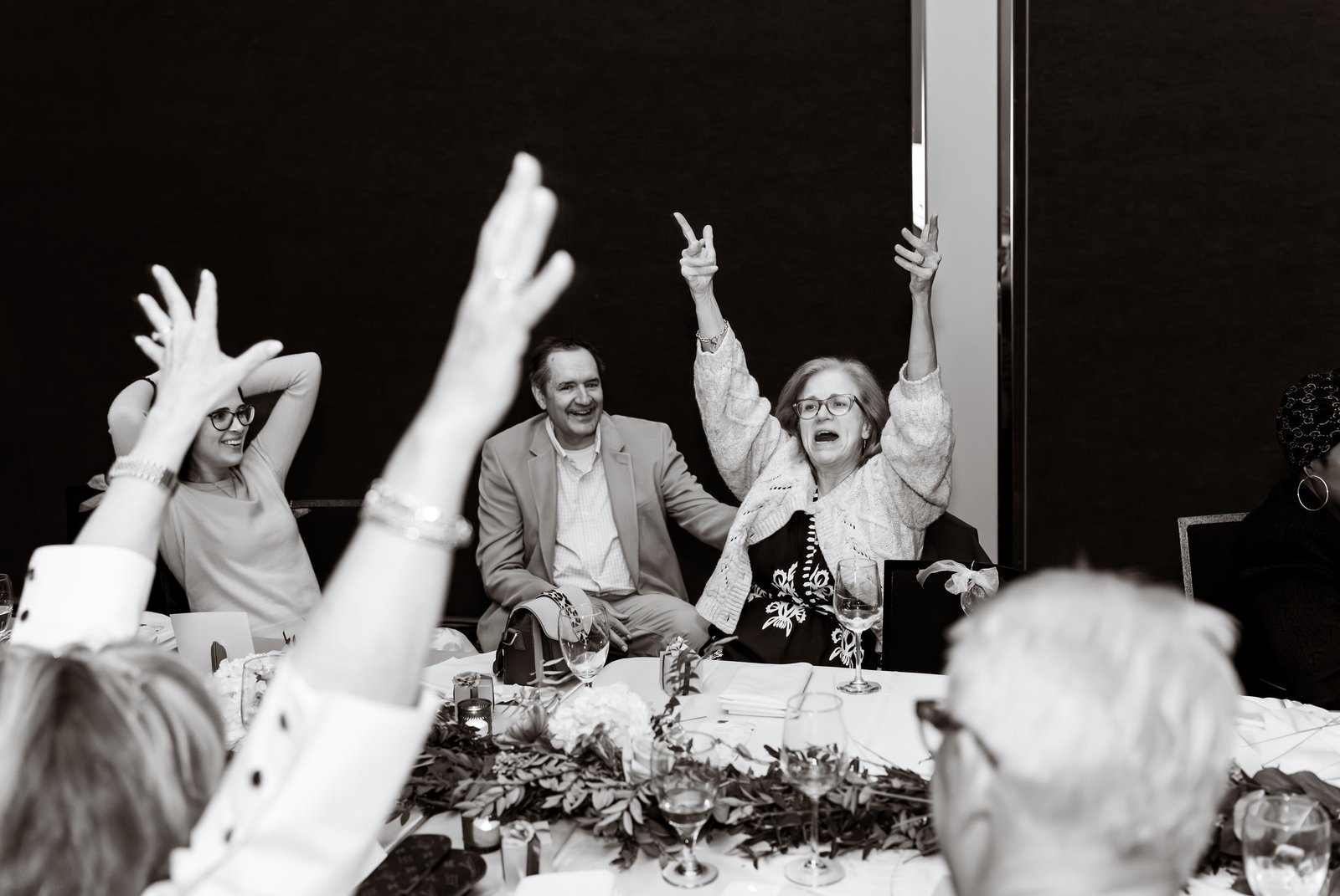 Guests raise their hands and cheer in black and white