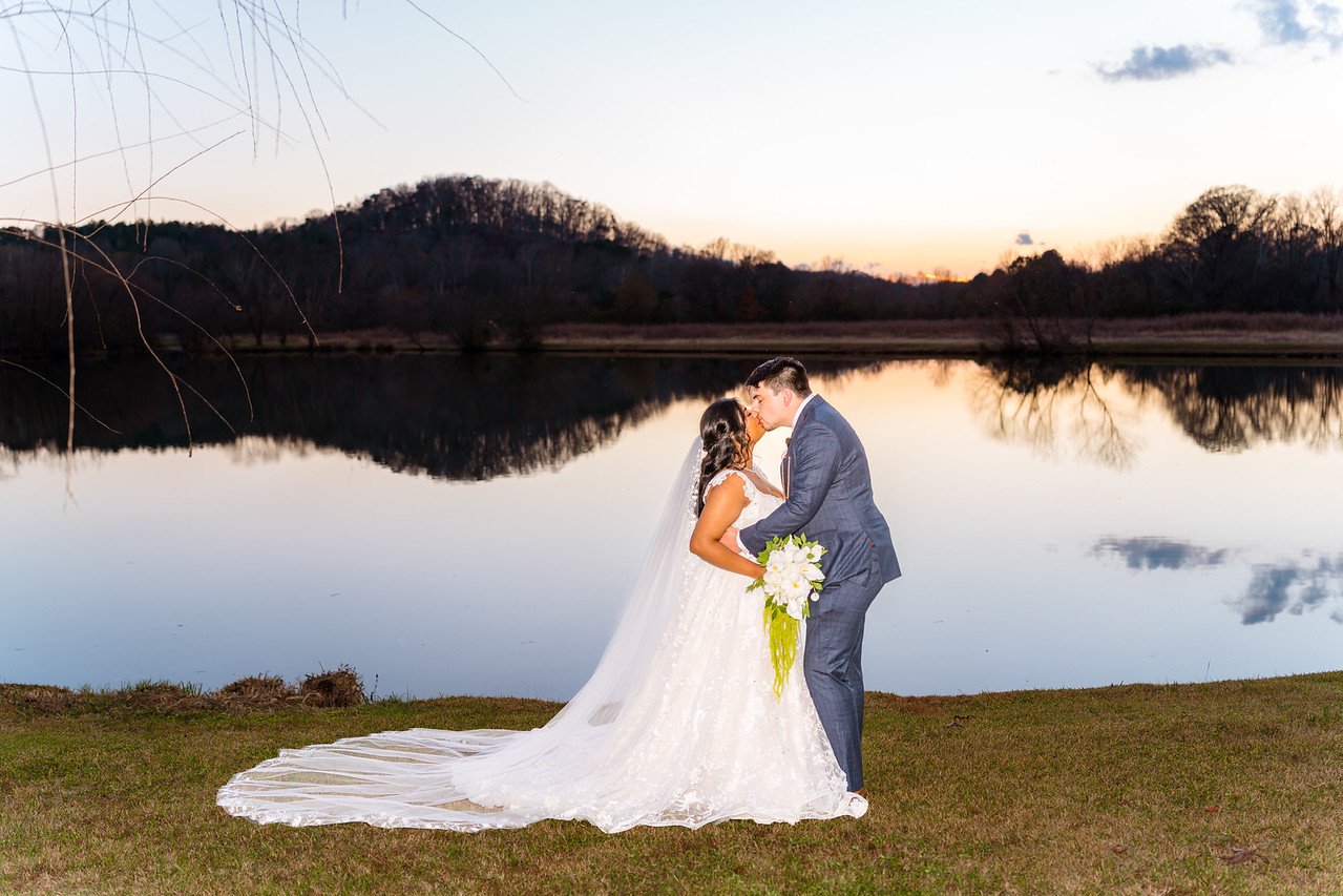 Reeham and Logan kiss beside the lake at Spring Lake Events in Rockmart
