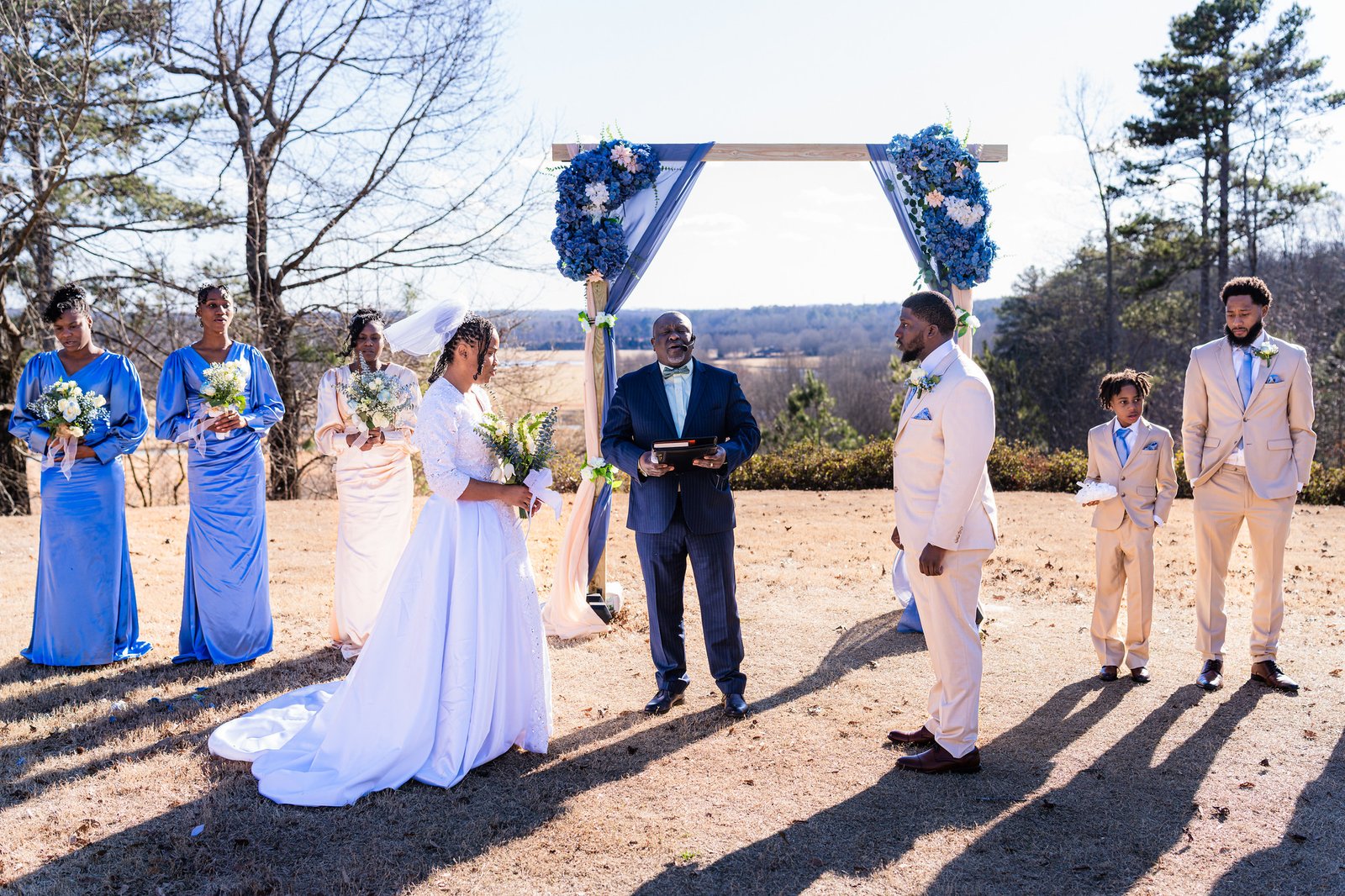 Tanjana and Marcel beneath a blue floral arch at their outdoor ceremony