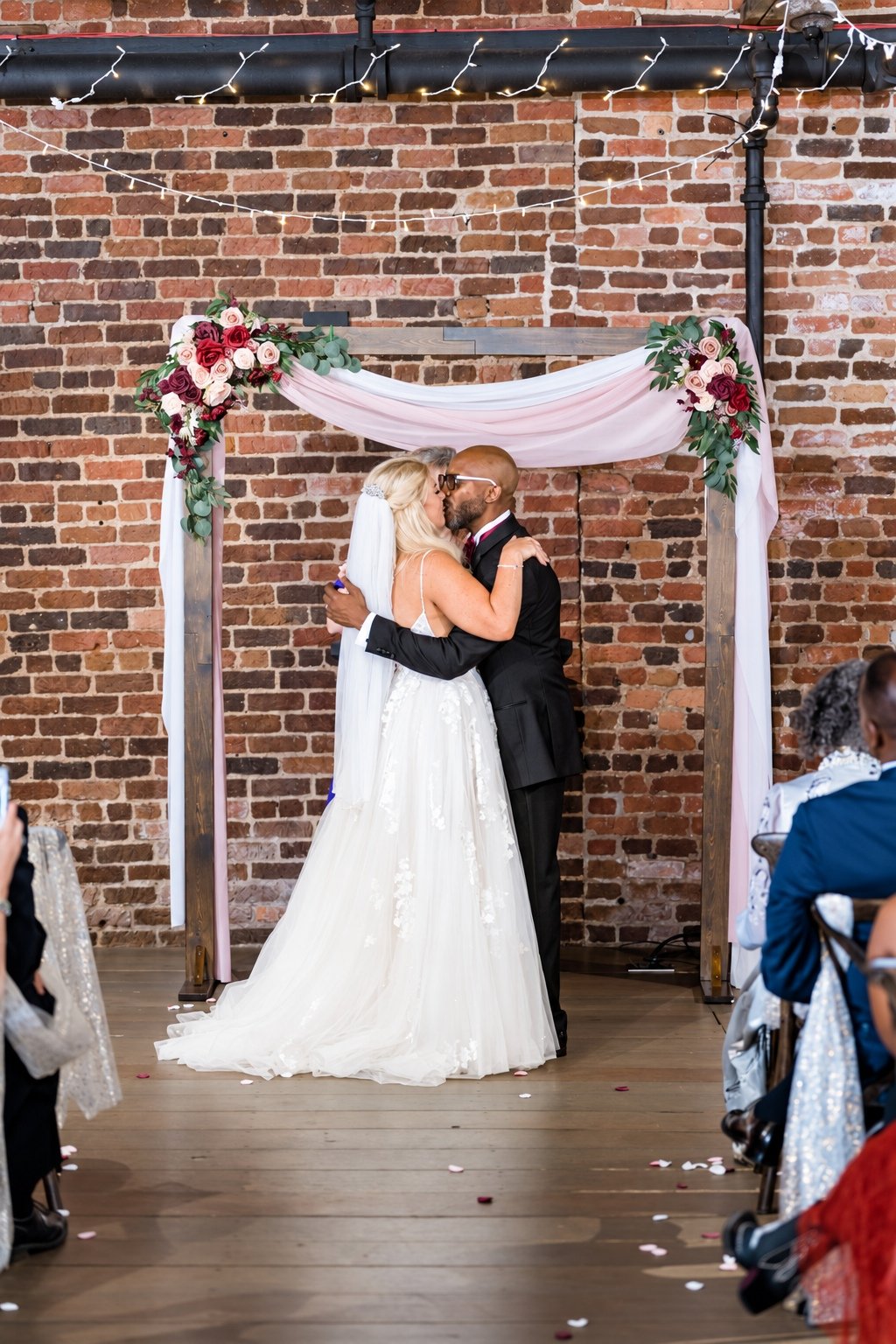 Franz and Mikayla’s ceremony kiss beneath the floral arbor