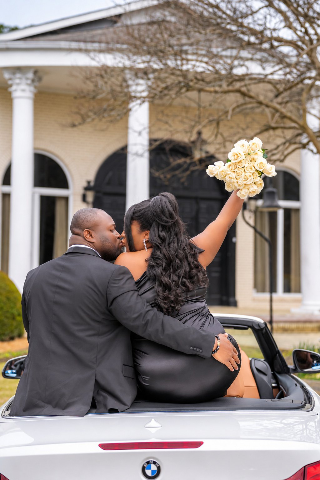 Kobina and Tiara sharing a kiss while seated in the white convertible