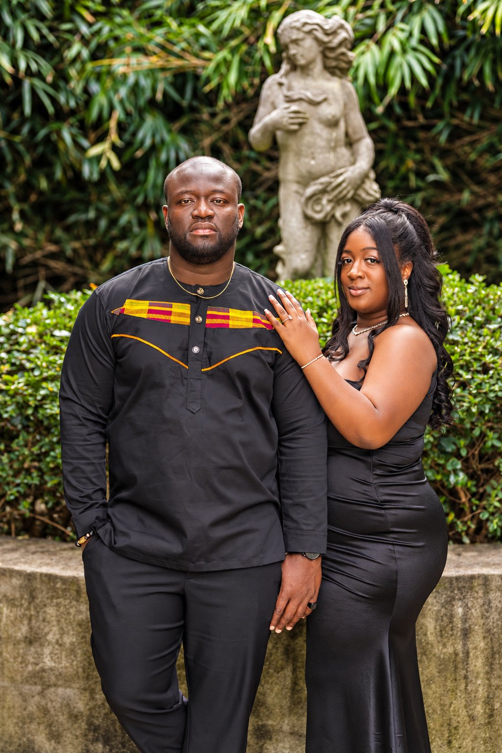 Couple together with a garden statue behind them