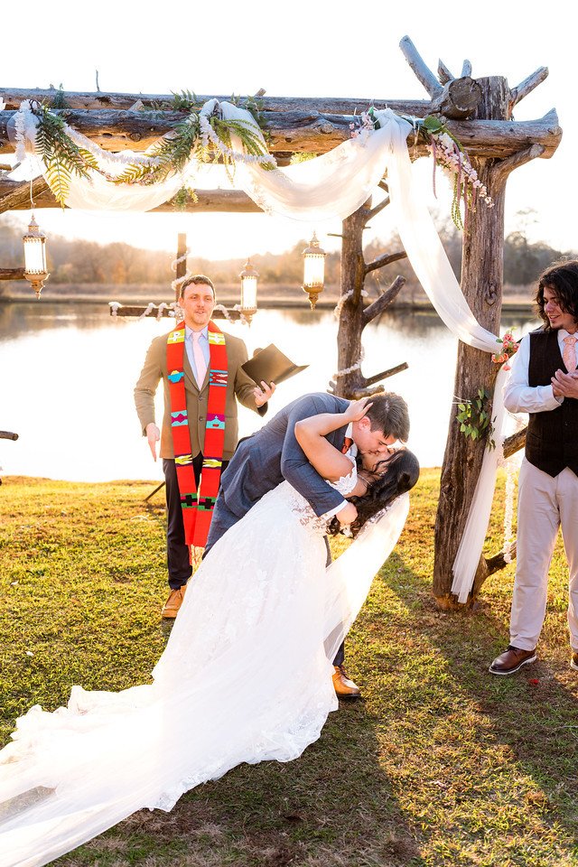 Logan dips Reeham for a kiss beneath the wedding arbor