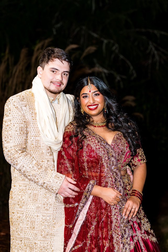 Reeham and Logan smile together in red and ivory evening attire